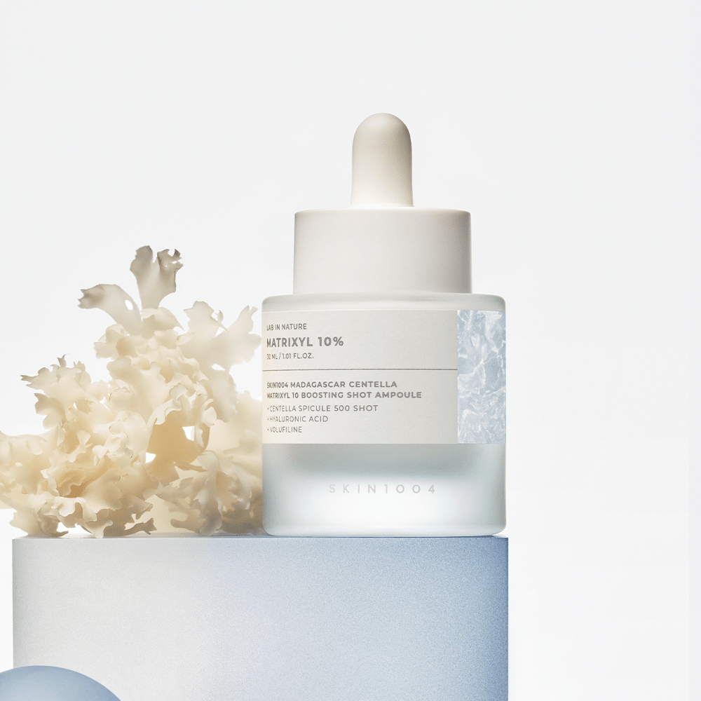 SKIN1004 Matrixyl 10 Boosting Shot Ampoule sobre pedestal con coral