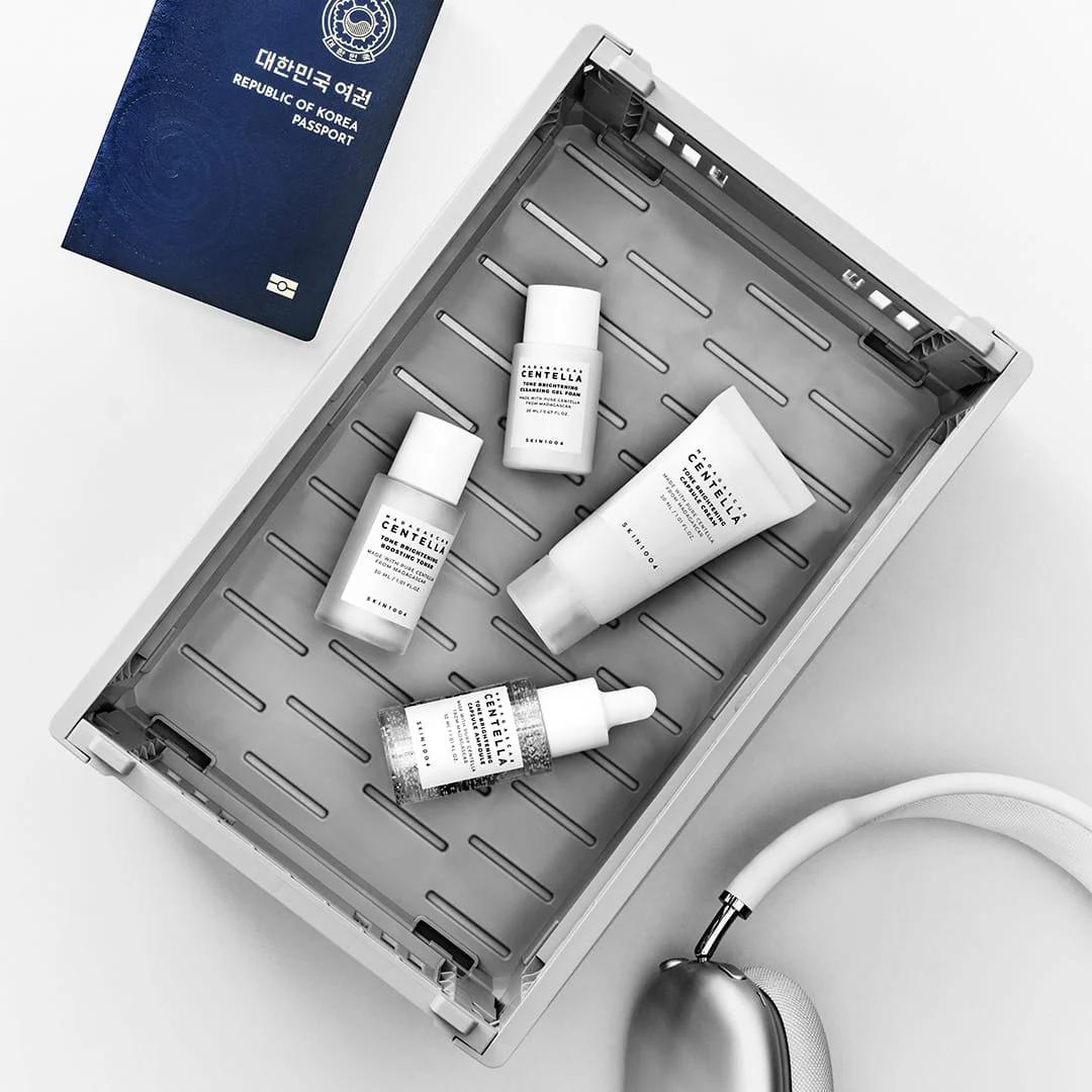 SKIN1004 Tone Brightening Travel Kit minis de viaje junto a pasaporte